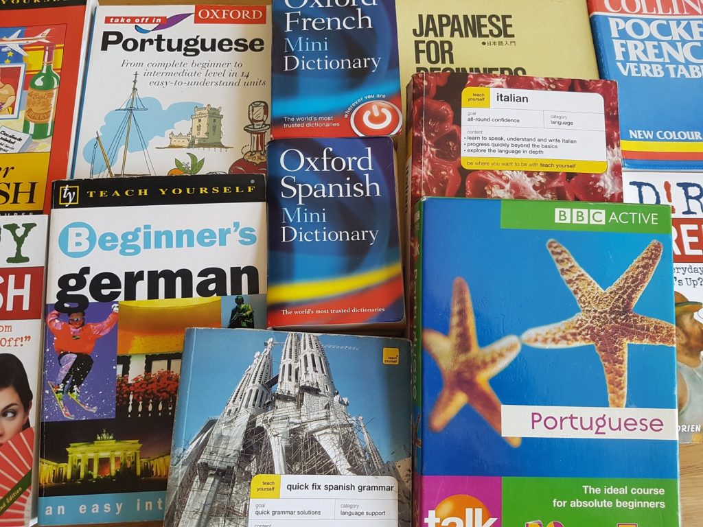 A series of language books from around the world on a desk.