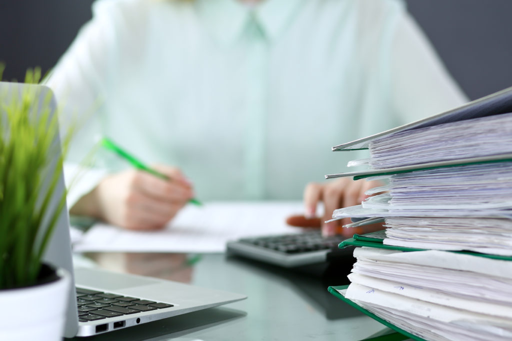 business man at desk with calculator stack of paper and laptop